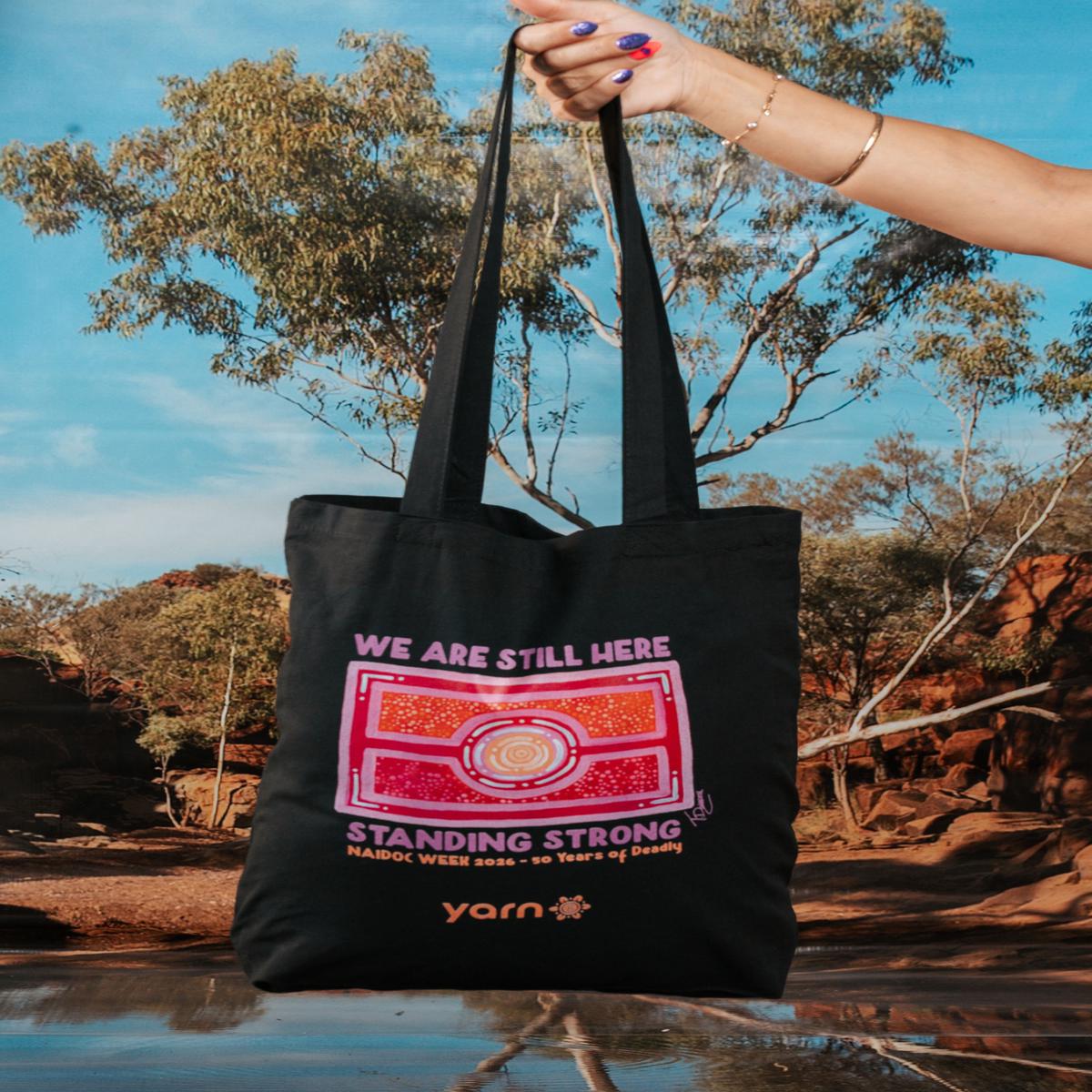 We Are Still Here NAIDOC Week 2026 Tote Bag Black Long Handle Cotton Tote Bag